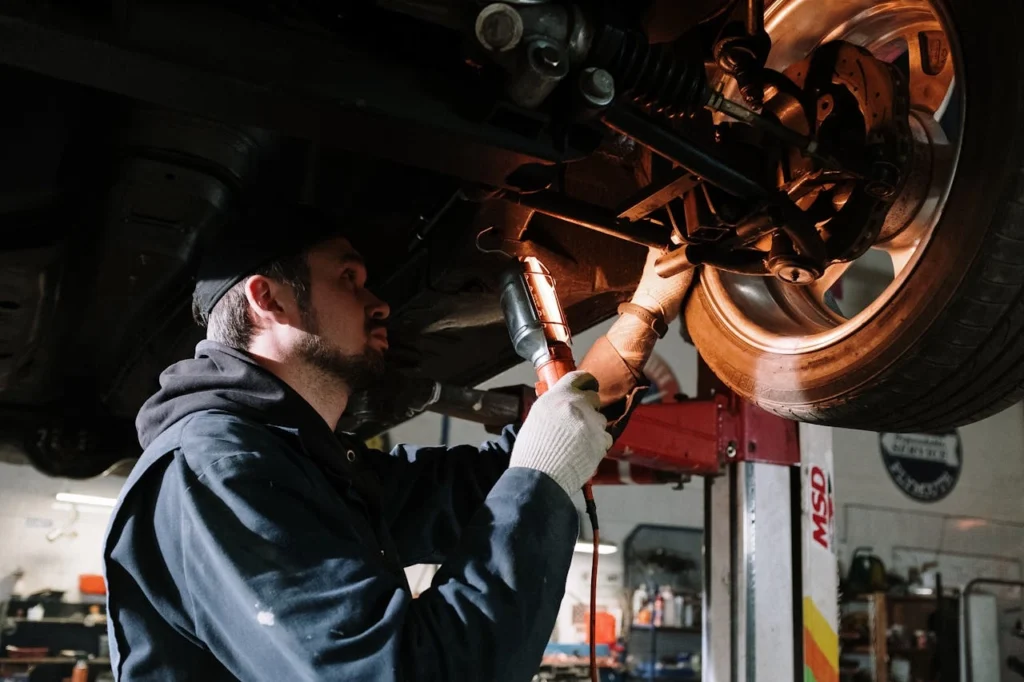 Mechanic examining vehicle undercarriage for auto repair and preventative maintenance at Firestone Buckner.