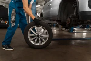 Mechanic in automotive shop inspecting tire and wheel alignment.